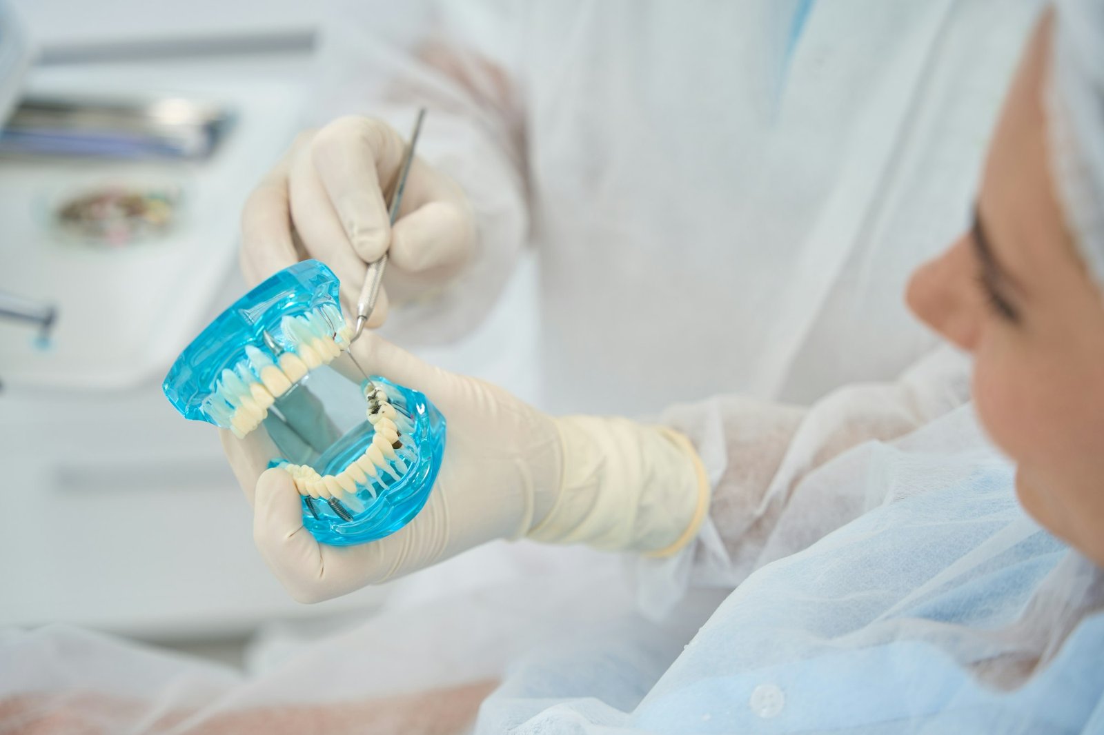 Doctor orthodontist shows patient model with dental implants and veneers, . donident, dental clinic